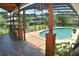 View of a sparkling pool enclosed with a screen, complemented by lush landscaping and an outdoor seating area at 225 Temple Cir, Eustis, FL 32726