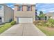 Charming two-story home featuring a two-car garage, red shutters, and a well-maintained front yard at 163 Tiny Flower Rd, Davenport, FL 33837
