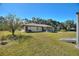 Side view of the house, showing the large backyard with an American flag and mature trees at 4680 Poinciana Dr, Indian Lake Estates, FL 33855