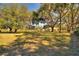Large grassy front yard with mature trees and a home in the background at 4680 Poinciana Dr, Indian Lake Estates, FL 33855