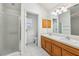 Bathroom featuring double sinks, wooden cabinets, a large mirror, and a walk-in shower at 515 Torres Pl, Lady Lake, FL 32159