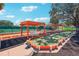Outdoor bocce ball court surrounded by a tennis court, lush landscaping, and orange-striped awnings, perfect for recreational play at 515 Torres Pl, Lady Lake, FL 32159