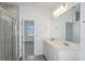 Modern bathroom featuring a double vanity, large mirror, neutral tile, and glass-enclosed shower at 6805 Sw 90Th Loop, Ocala, FL 34476