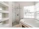 Well-lit bathroom featuring a glass-enclosed shower, bathtub, and built-in shelving at 2504 Davenport Cir, Kissimmee, FL 34746