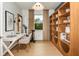 Bright home office featuring a white desk, accent chair, built-in shelving, and workout equipment near the window at 6785 Sw 90Th Loop, Ocala, FL 34476