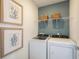 Bright laundry room featuring washer, dryer, wire shelving, and framed wall art at 6788 Sw 90Th Loop, Ocala, FL 34476