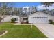 House exterior showcasing a two-car garage and lush green lawn at 1309 Ballesteros Dr, The Villages, FL 32162