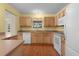 Bright kitchen with light wood cabinets, white appliances, and laminate flooring at 1309 Ballesteros Dr, The Villages, FL 32162