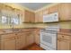 Bright kitchen with light wood cabinets, white appliances, and laminate flooring at 1309 Ballesteros Dr, The Villages, FL 32162