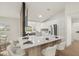 Bright, open-concept kitchen features white cabinetry, a quartz countertop island with seating, and stainless steel appliances at 27100 Racquet Cir, Leesburg, FL 34748