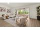 Bright living room with wood floors, modern furniture, artwork, and a sliding glass door to a sunroom at 27100 Racquet Cir, Leesburg, FL 34748