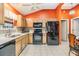 Full view of kitchen with black appliances and orange walls at 3096 Lansing Way, The Villages, FL 32162
