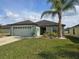 Inviting single-story home with attached garage and lush green lawn with a palm tree at 2157 Geneva Dr, Lakeland, FL 33805