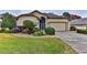 Tan one-story house with landscaped yard, attached garage, and driveway at 706 Lake Diamond Ave, Ocala, FL 34472