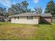 Home exterior featuring tan siding, dark shutters, and a lawn at 5040 Kirkland Rd, Lakeland, FL 33811