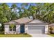 Charming single-story home with a well-manicured lawn, a blue door, and an attached two-car garage at 8223 Sw 52Nd Lane Rd, Ocala, FL 34481