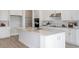 This kitchen features an expansive island, white cabinets, stainless appliances, and a stylish tile backsplash at 5222 Sw 88Th Cir, Ocala, FL 34481