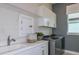 Bright laundry room features modern washer/dryer, sink, white cabinetry, and ample countertop space for folding at 5222 Sw 88Th Cir, Ocala, FL 34481