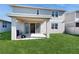 Covered patio and grassy backyard with a home in the background at 1076 Sugarwood St, Davenport, FL 33837