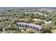 Aerial view of an apartment building surrounded by trees, with a distant view of other buildings and a lake at 150 El Dorado # 101, Winter Haven, FL 33884