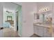 A clean bathroom with a large mirror and a view of a bedroom with a ceiling fan and a dresser at 4064 River Crest Cir, Leesburg, FL 34748