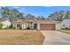 Charming single-Gathering home features a well-manicured lawn, neutral siding, brown shutters, and a two-car garage at 4064 River Crest Cir, Leesburg, FL 34748
