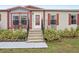 Steps leading to front door of manufactured home with red trim and landscaping at 555 Lindsey Dr, Lakeland, FL 33809