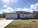 Single-story home with gray exterior, two-car garage, and landscaped lawn at 310 Amberjack Ln, Poinciana, FL 34759