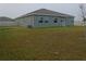 Green backyard with an air conditioning unit, multiple windows and a sliding glass door at 400 Watusi Way, St Cloud, FL 34772