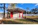 Red metal storage shed with a roll-up door and covered carport at 3720 Willis Rd, Mulberry, FL 33860