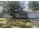 White brick ranch house with a single car garage and mature tree in the front yard at 4534 Lemans Dr, Orlando, FL 32808