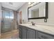 Bright bathroom featuring a glass shower, grey vanity with a stylish framed mirror, and neutral tile flooring at 801 13Th Ne Ct, Winter Haven, FL 33881