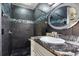 Modern bathroom featuring black tile shower, mosaic accent, and granite countertop with oval mirror at 8309 W Lake Marion Rd, Haines City, FL 33844