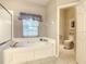 Clean and well maintained bathroom showcasing a soaking tub and toilet behind a privacy door at 417 Lake Butler Dr, Kissimmee, FL 34759