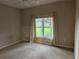 Neutral carpeted bedroom with a large window overlooking the front yard, offering ample natural light at 417 Lake Butler Dr, Kissimmee, FL 34759