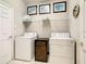 Functional laundry room with washer, dryer, shelving, and tiled floor at 417 Lake Butler Dr, Kissimmee, FL 34759