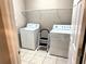 Bright laundry room with washer, dryer, tile floor and shelving at 417 Lake Butler Dr, Kissimmee, FL 34759