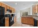 Well-lit kitchen with wooden cabinets, black appliances, ceramic tile floor, and a view of the backyard at 536 Cheshire Way, Davenport, FL 33897