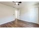 Bright bedroom with wood floors, a ceiling fan, a closet and a door to bathroom providing style and function at 116 Woodlane Ave, Wildwood, FL 34785