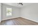 Bright bedroom featuring wood floors, a ceiling fan, and natural light from a large window at 116 Woodlane Ave, Wildwood, FL 34785