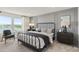 Serene bedroom with a black metal bed frame, neutral color palette, and a view of the outdoors at 9064 Wildlight Trl, Wildwood, FL 34785