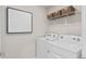 Functional laundry room with a modern washer and dryer, complemented by organized shelving and contemporary artwork at 9064 Wildlight Trl, Wildwood, FL 34785