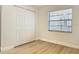 Bright bedroom with a large window and closet featuring light wood-look floors and white trim at 610 Moonpenny Cir, Port Orange, FL 32127