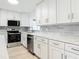 Bright kitchen with stainless steel appliances, white cabinets, gray backsplash, and laminate flooring at 610 Moonpenny Cir, Port Orange, FL 32127