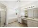 Bright bathroom featuring a bathtub, shower, dual sink vanity and white cabinets at 8867 Pebblebrooke Dr, Lakeland, FL 33810