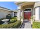 Inviting front entrance with a red double door, lush landscaping, and elegant decorative features at 8867 Pebblebrooke Dr, Lakeland, FL 33810