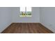 Minimalist bedroom features hardwood floors, white walls, baseboard trim, and natural light from window at 5295 Sw 87Th Ter, Ocala, FL 34481