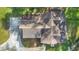 Aerial view of a home with dark roof, driveway, and surrounding trees, captured from directly above the residence at 114 Tempsford Rd, Auburndale, FL 33823