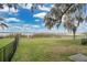 Expansive fenced backyard with lush lawn, mature trees, and a serene view of the lake at 114 Tempsford Rd, Auburndale, FL 33823