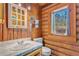 Charming log-cabin bathroom featuring wood walls, a window, and a vanity with white tile countertop at 114 Tempsford Rd, Auburndale, FL 33823